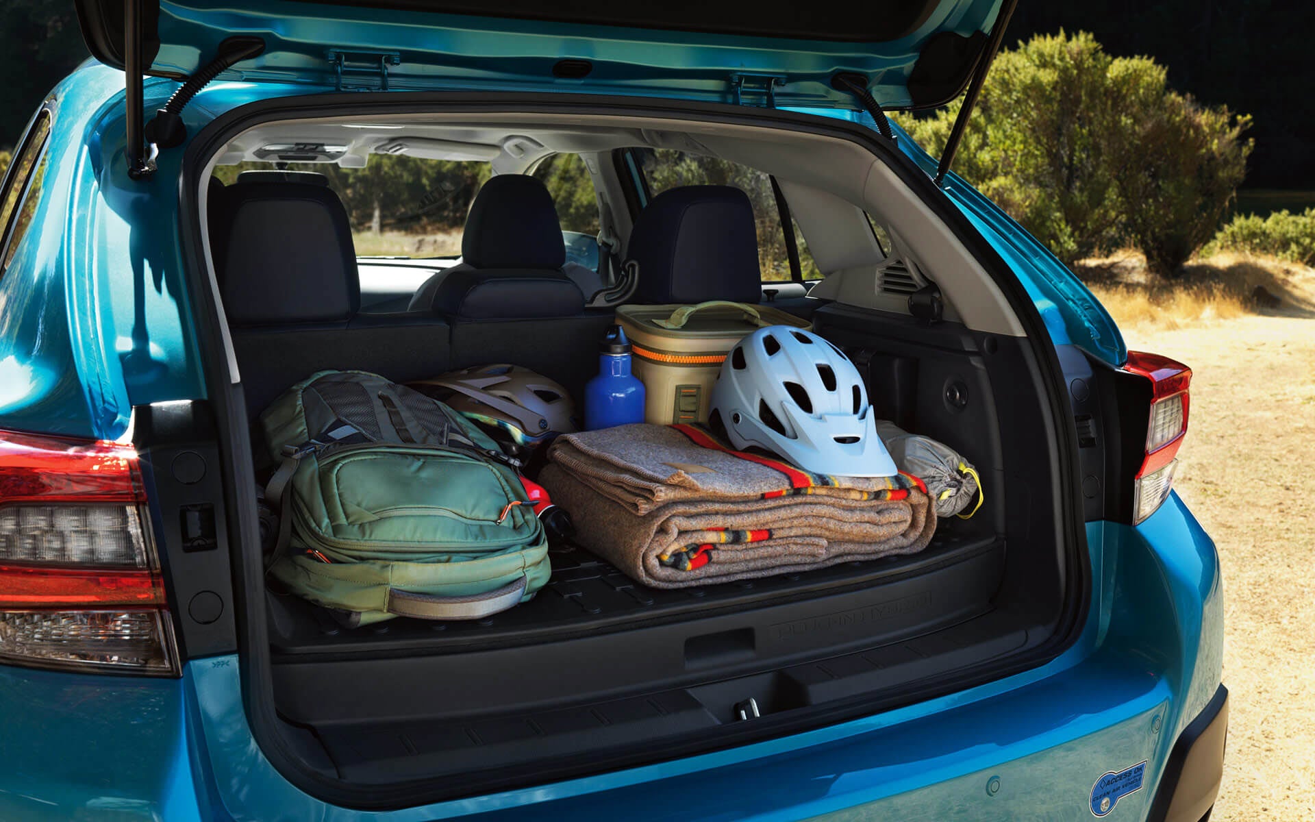 A backpack, blanket, and bike helmet in the rear cargo area of a Crosstrek Hybrid | Open Road Subaru in Union NJ